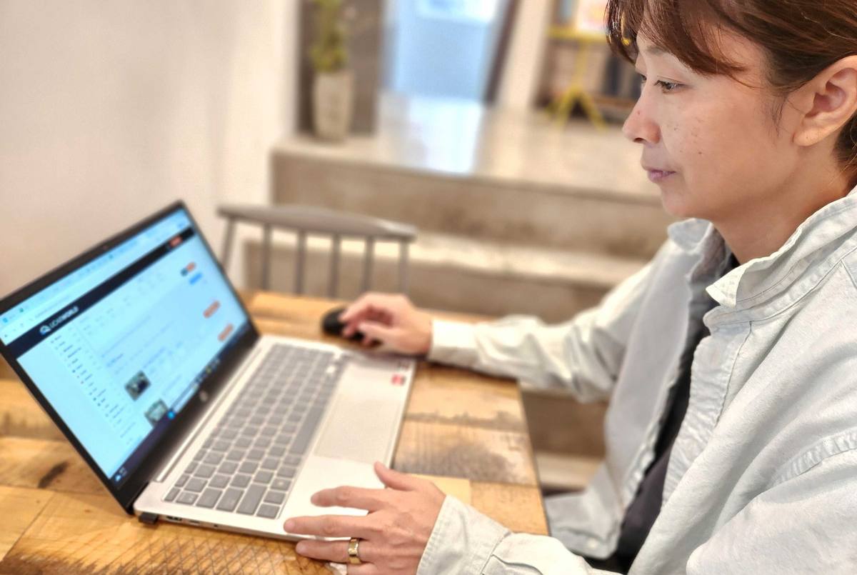 A UCARWORLD team member reviewing vehicle listings on a laptop at a wooden desk