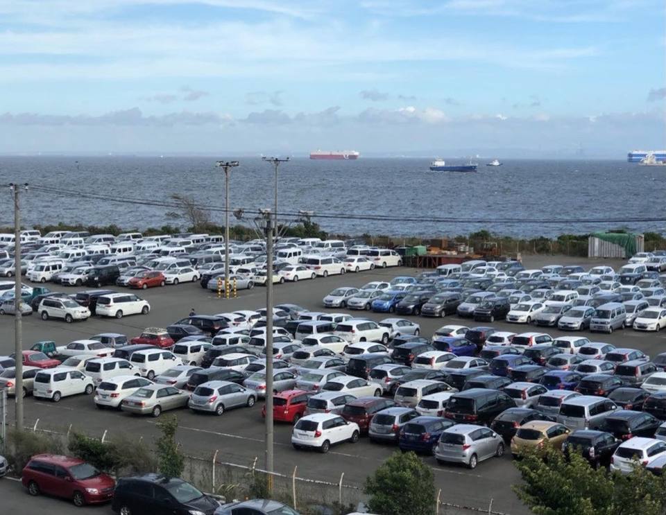 Vehicles lined up at an export yard by the sea in Japan