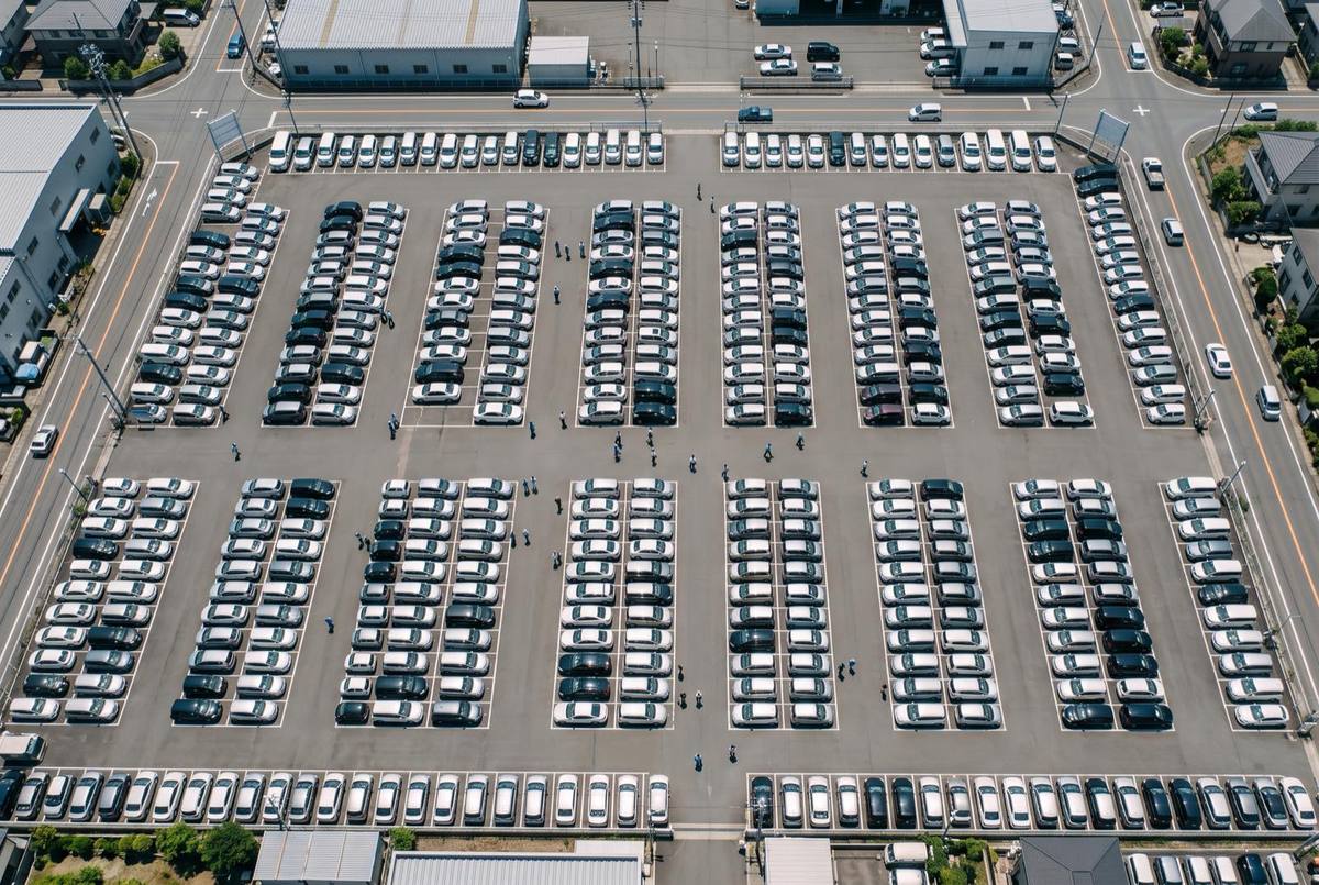 Aerial view of rows of used cars lined up at a large dealership lot in Japan